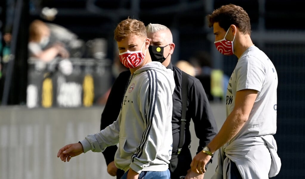 <p>Spelers van Bayern München dragen een mondkapje voorafgaand aan een wedstrijd tegen Borussia Dortmund. Topsporters lopen mogelijk extra risico op hartschade door het coronavirus.</p> (beeld epa / Federico Gambarini)