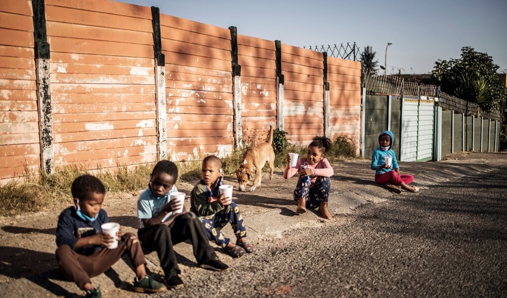 Kinderen in Zuid-Afrika met het ontbijt dat is verstrekt door een non-profitorganisatie. (beeld afp / Marco Longari)