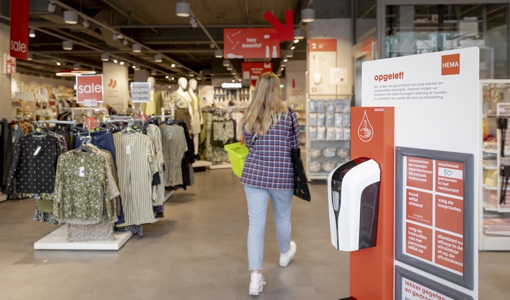 Klanten desinfecteren hun handen in verband met corona bij de ingang van de HEMA in Eindhoven. (beeld anp / Robin van Lonkhuijsen)