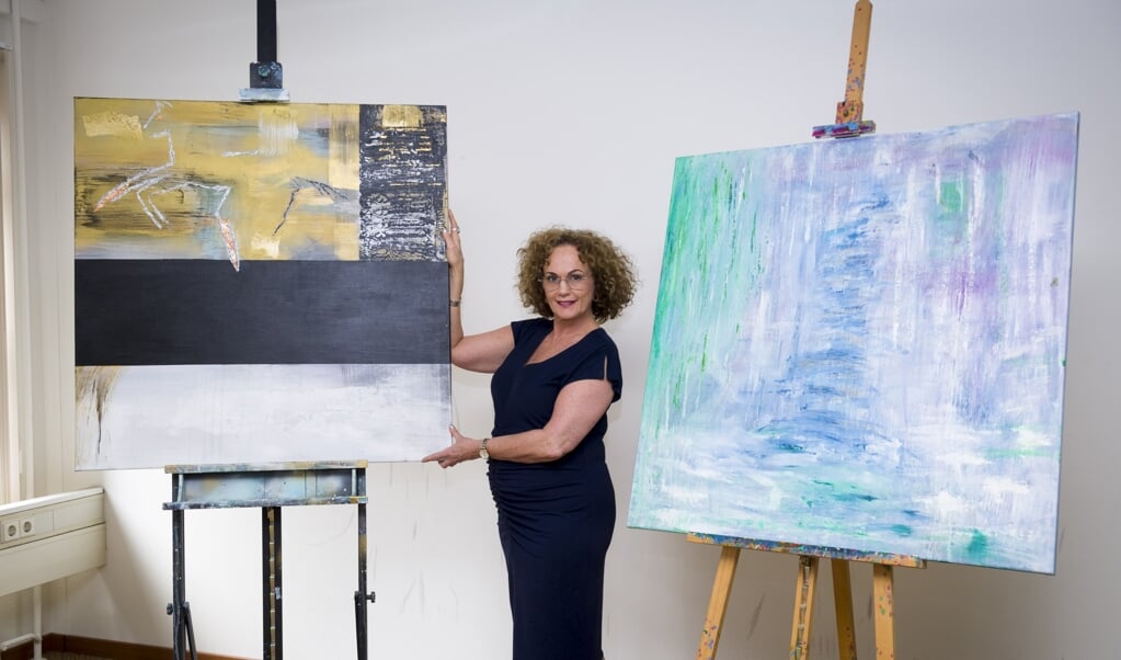 Juanita van der Groep in haar atelier, met haar werk over het witte en zwarte paard. (beeld Richard van Hoek)