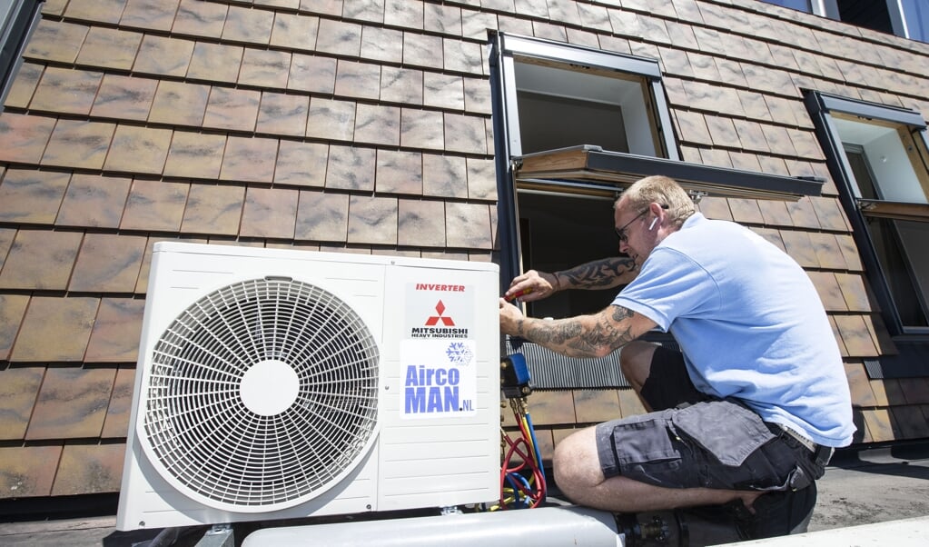 Een installateur plaats een airconditioner in een woning in Hooglanderveen. Door het warme weer gaan mensen op zoek naar verkoeling in hun huis. (beeld anp / Pieter Stam de Jonge)