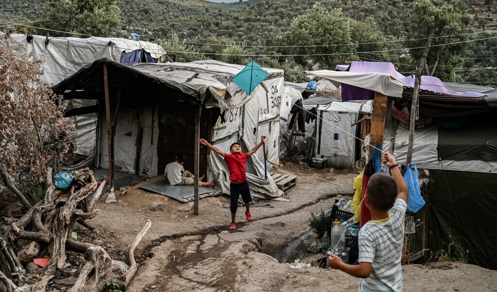 Twee kinderen spelen met een vlieger tussen de geïmproviseerde tenten van vluchtelingenkamp Moria op het Griekse eiland Lesbos. In het kamp bevinden zich zo'n zevenhonderd alleenstaande minderjarige asielkinderen. (beeld afp / Aris Messinis)