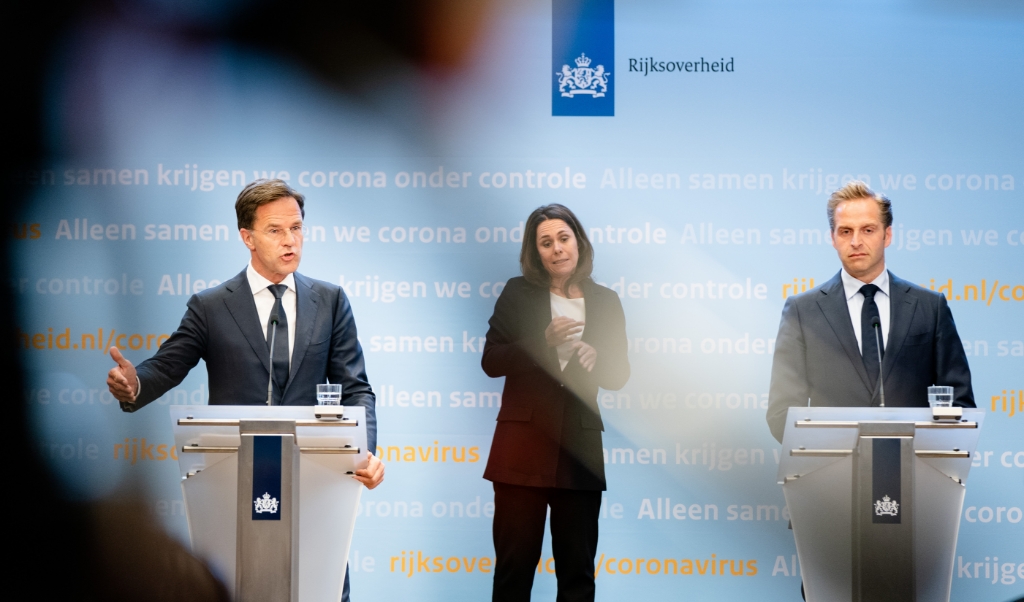 Premier Mark Rutte, coronaminister Hugo de Jonge en gebarentolk Irma Sluis tijdens de persconferentie over de coronacrisis. (beeld anp / Bart Maat)