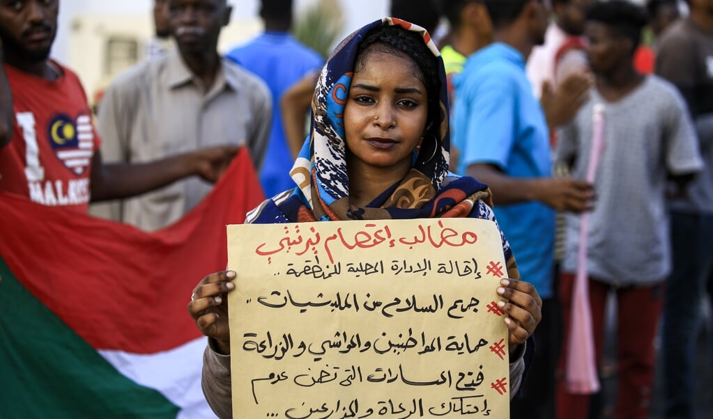 Een demonstrant houdt een bord omhoog met daarop de eisen van de bevolking van Darfur, tijdens een solidariteitsprotest in Khartoem deze week. (beeld afp / Ashraf Shazly)