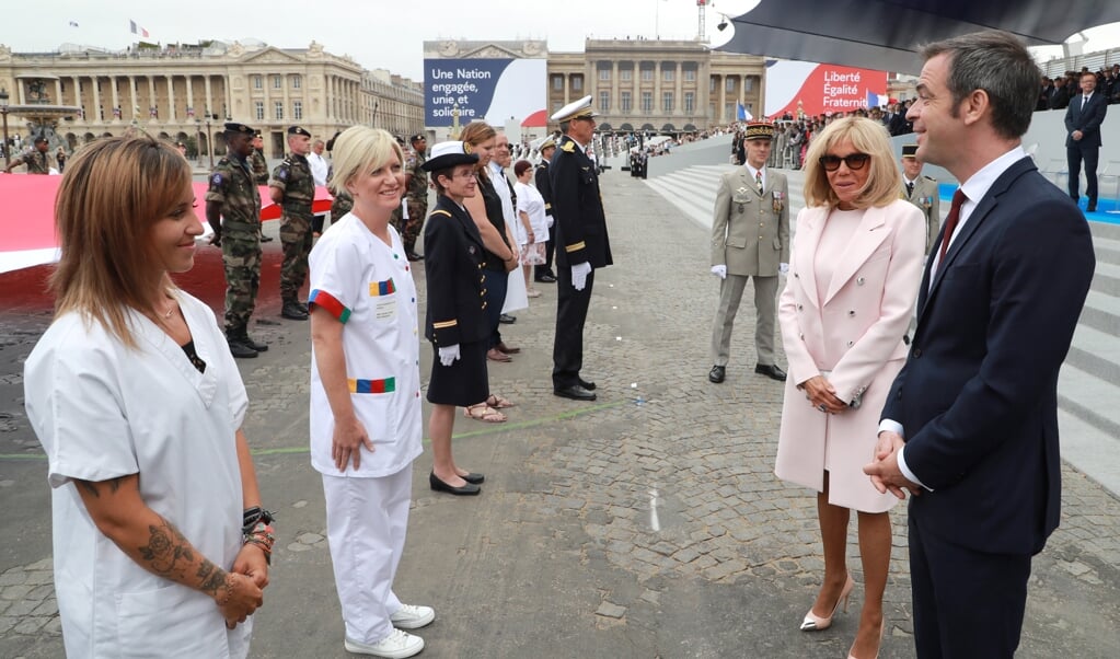 De Franse minister van Gezondheidszorg Olivier Véran (rechts) en first lady Brigitte Macron spreken met zorgpersoneel. (beeld epa / Ludovic Marin)