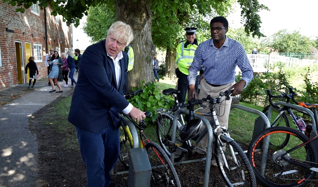 De Britse premier Boris Johnson (links) en het parlementslid Darren Henry stallen hun fiets in Beeston, central England. Hiermee begon vorige week een actie om Britten te stimuleren te gaan fietsen ten behoeve van hun gezondheid. De overheid beloofde nieuwe fietsstroken aan te leggen. (beeld afp)