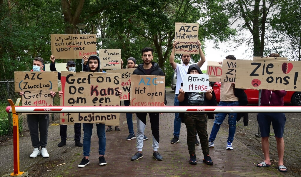 Voor de poort van het asielzoekerscentrum in Zweeloo protesteren asielzoekers, eind juli, tegen de ongelijke behandeling van asielaanvragen. (beeld Marcel van den Bergh)