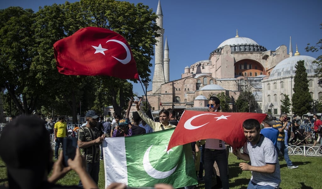 Mensen poseren met Turkse en Pakistaanse vlaggen bij de Hagia Sophia uit vreugde dat deze weer een moskee is geworden. (beeld Epa/Erdem Sahin)