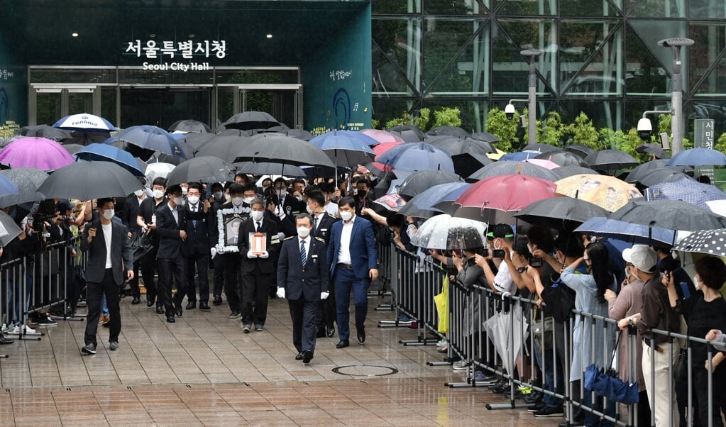 In de stromende regen brengen inwoners van Seoul de laatste eer aan hun overleden burgemeester Park Won-soon. (beeld afp / Jung Yeon-je)