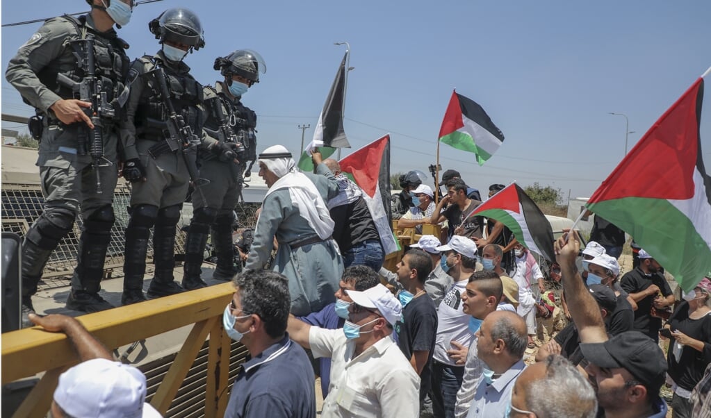 Israëlische grenstroepen houden een oog op Palestijnen. Die demonstreren tegen de plannen van de Israëlische premier Benjamin Netanyahu om delen van de Westoever te annexeren. (beeld afp / Jaafar Ashtiyeh)