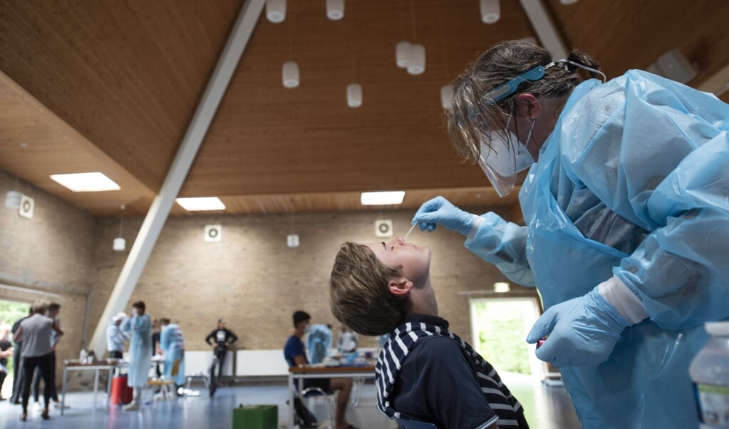 <p>Een jongen wordt op een testlocatie op Terschelling getest op het coronavirus. Omdat de laboratoria op dit moment niet genoeg testen kunnen verwerken, worden op verschillende plekken in het land teststraten maar deels gebruikt.</p> (beeld anp / Jacob van Essen)