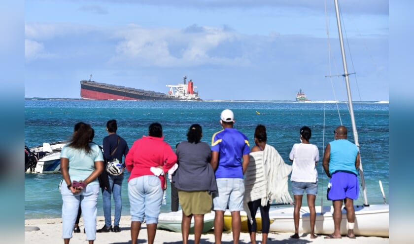 Inwoners van Mauritius kijken naar de vastgelopen olietanker Wakashio. Het eiland heeft buitenlandse hulp nodig om een milieuramp te voorkomen. (beeld afp)
