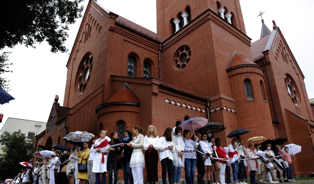 <p>Vrouwen demonstreren bij de 'rode' Simon en Helena, een rooms-katholieke kerk in Minsk, Belarus.</p> (beeld Epa/tatyana Zenkovich)