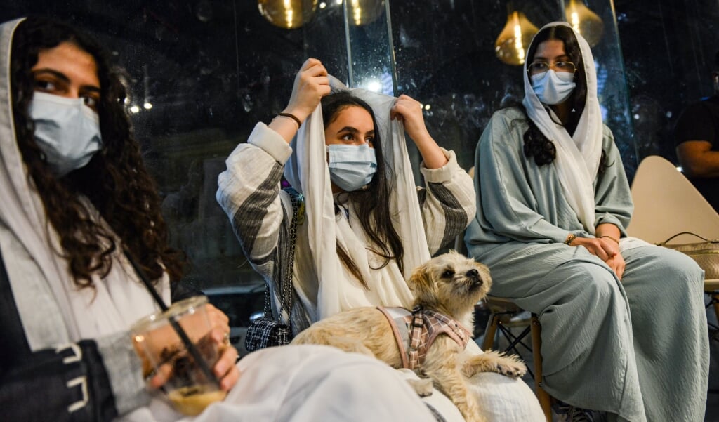 <p>Vrouwen in een deze zomer geopend café in Khobar, het eerste café waar honden welkom zijn. Honden worden in Saoedi-Arabië traditioneel als onrein gezien. </p> (beeld Fayez Nureldine / afp)