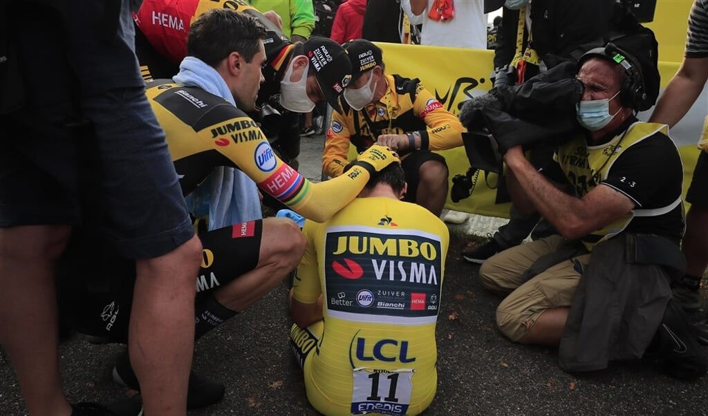 Primoz Roglic zit verslagen op de grond. Hij wordt getroost door Tom Dumoulin. (beeld Hollandse Hoogte / AFP)