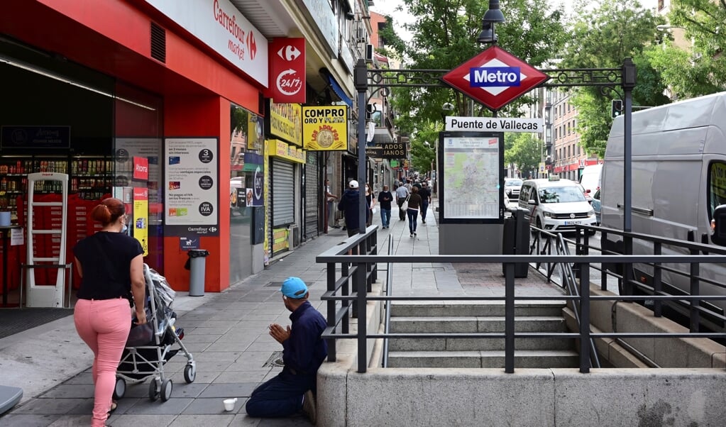 <p>Een bedelaar in de buitenwijk Vallecas in Madrid. Alleen voor werk, school en strikt noodzakelijke boodschappen mogen de bewoners van sinds maandag hun buurt nog uit.</p> (beeld epa / Vã­tor Lerena)