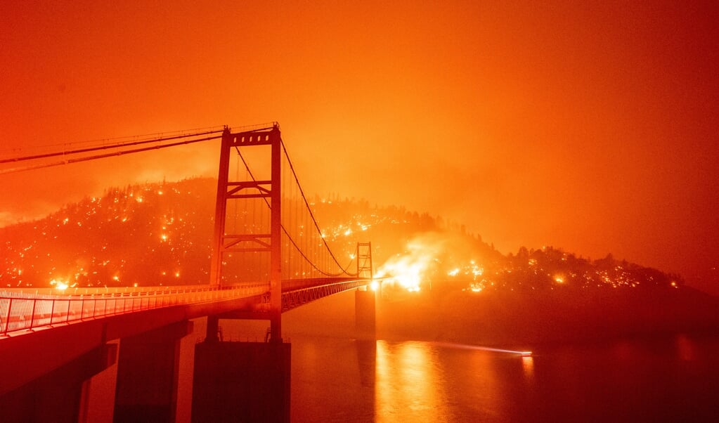 <p>Wind jaagt het vuur op bij Lake Oroville en verwoest de elektriciteitskabels die boven de grond lopen.</p> ( beeld AFP/Josh Edelso)