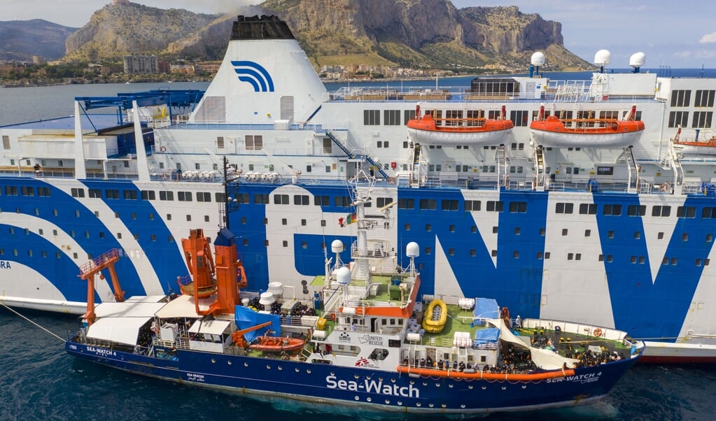 <p>De Sea-Watch 4 ligt langszij een veerboot om de honderden op zee geredde migranten over te zetten. Toen het schip vervolgens vrijdag werd gelast naar de haven te komen voor inspectie, werd het aan de ketting gelegd.</p> (beeld afp / Thomas Lohnes)