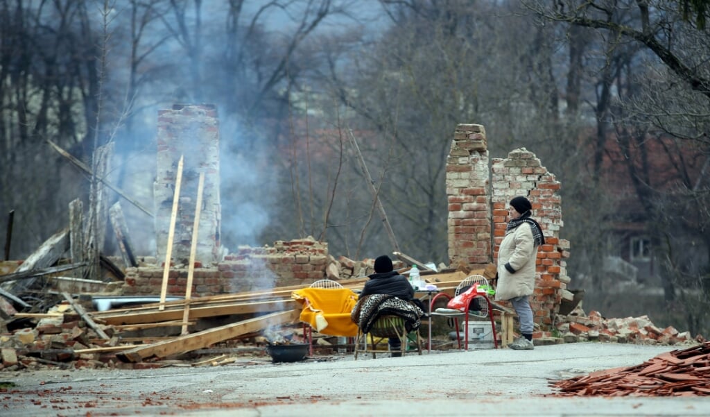 Dakloos geworden Kroatische vrouwen voor hun voormalige woning in Petrinja. (beeld afp / DAMIR SENCAR )