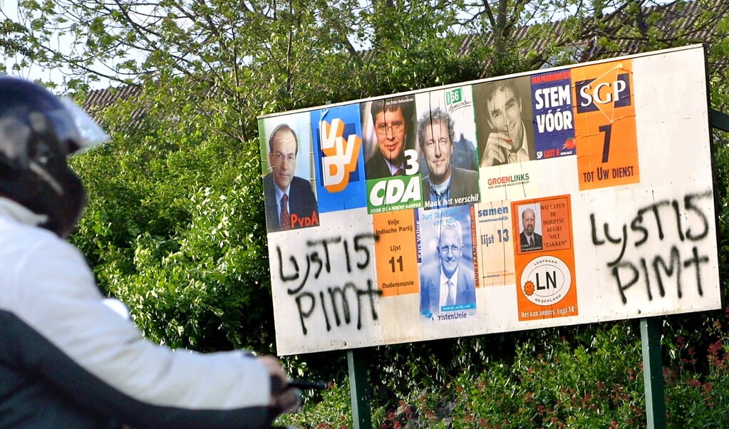 Vlak voor de Tweede Kamerverkiezingen in 2002 werd Pim Fortuyn op 6 mei 2002 vermoord, de lijsttrekker van de LPF, de Lijst Pim Fortuyn. Op dit bord ontbreekt de poster van de LPF, maar een aanhanger heeft met de verfspuit Lijst 15 Pim† twee keer op een lege plek gespoten. (beeld novum / Dirk Hol)