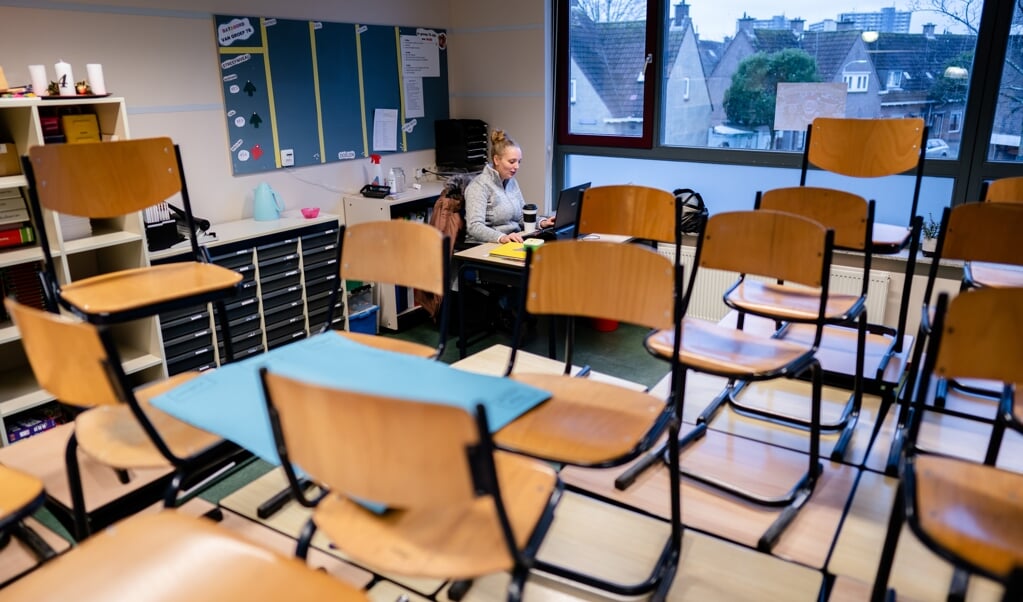 Juf Jessie van Groep 7 heeft in een leeg klaslokaal van basisschool Jeroen online contact met leerlingen. (beeld anp / Bart Maat)
