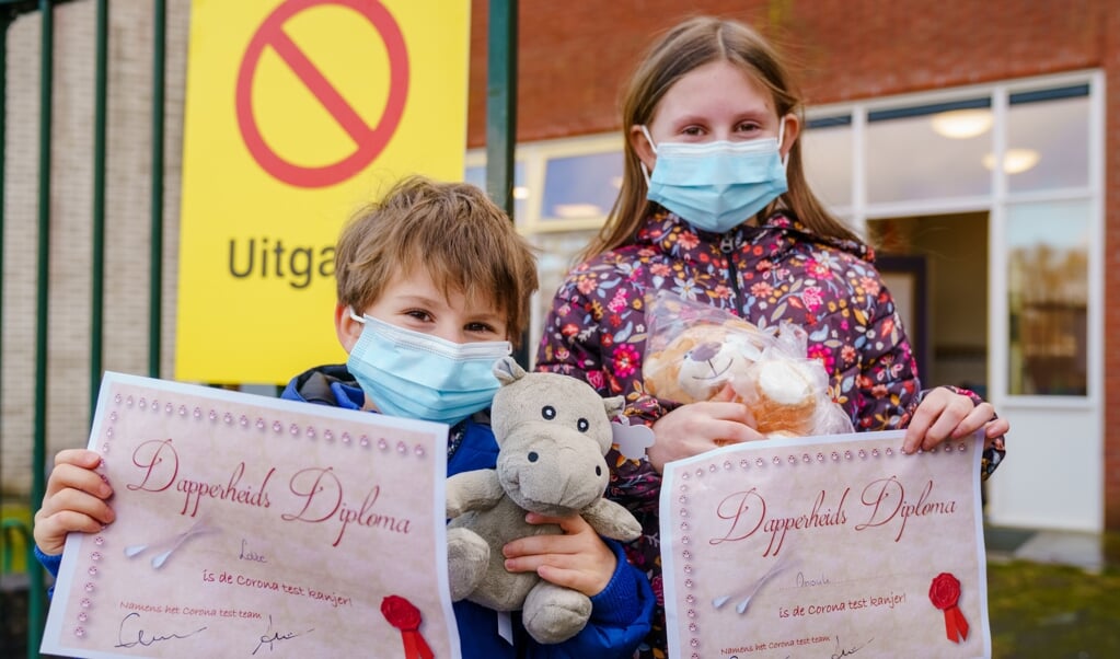Kinderen tonen een Dapperheids Diploma nadat ze zijn getest op het coronavirus in het dorp Bergschenhoek. (beeld anp / Marco de Swart)