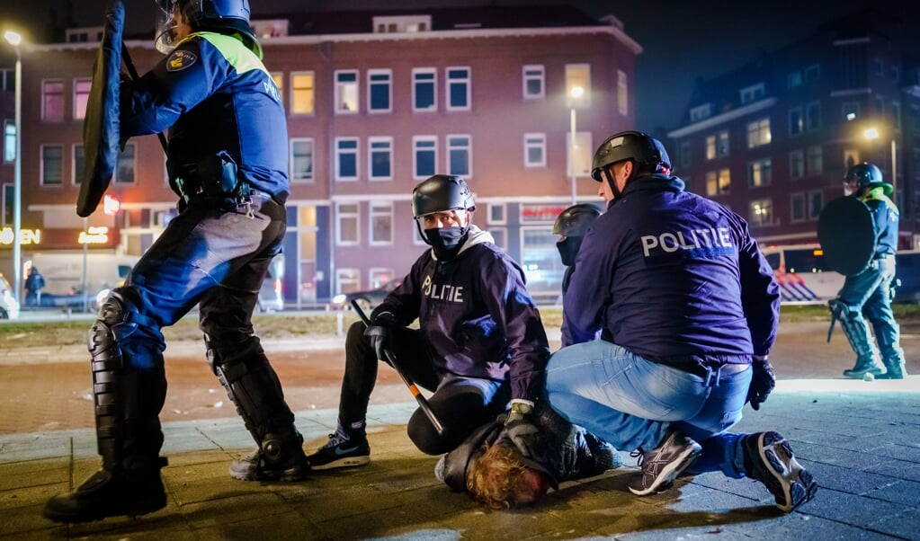 De politie arresteert een relschopper op de Beijerlandselaan in Rotterdam. (beeld anp / Marco de Swart)