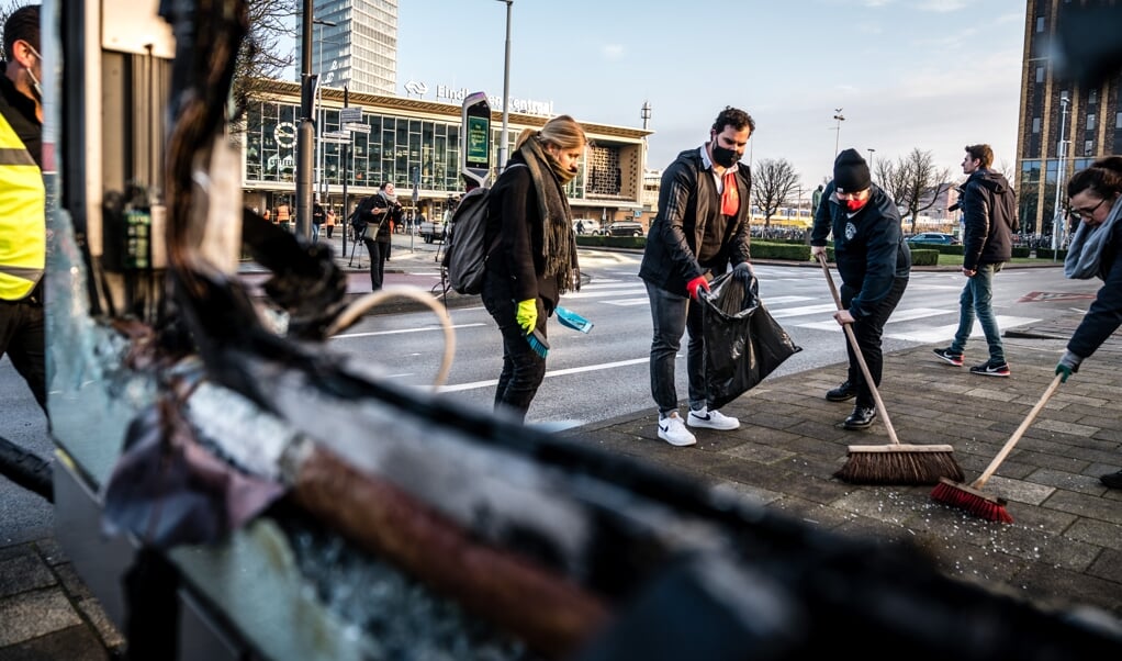 Vrijwilligers helpen in het centrum van Eindhoven bij het opruimen van de schade, na de rellen van afgelopen zondag. (beeld anp / Rob Engelaar)