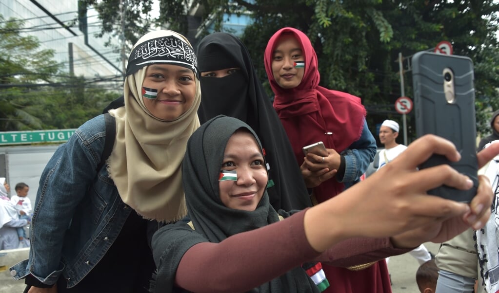 De MUI, de belangrijkste raad van geestelijken in Indonesië, organiseerde in 2017 een demonstratie tegen Donald Trump. Vier deelnemende vrouwen maken een selfie. (beeld / afp Photo / Adek Berry)
