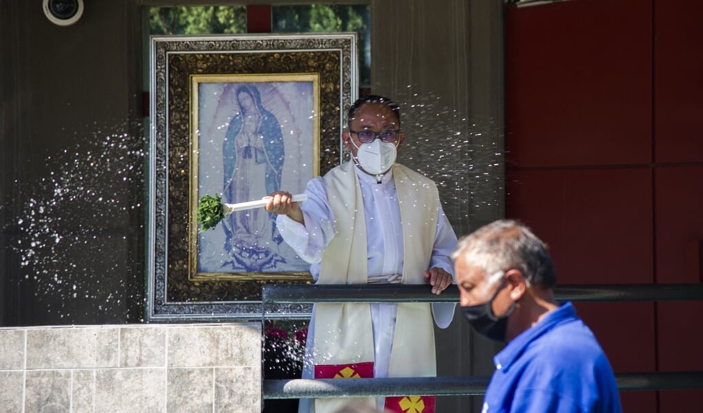 Een priester met mondkapje zegent de gelovigen in Mexico-Stad. Steeds minder Mexicanen noemen zich rooms-katholiek. (beeld afp / Claudio Cruz)