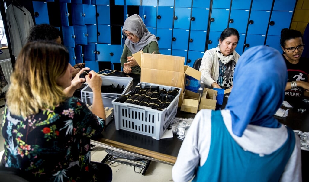 Statushouders aan het werk bij een re-integratiebedrijf. Het is lastiger fondsen werven voor hulp aan deze groep. (beeld anp / Jerry Lampen)