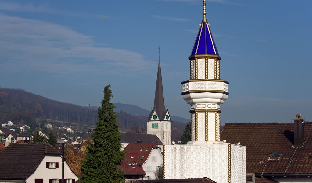 Minaret en kerktoren in een Zwitsers dorp. Volgens Olivier Roy groeit in Europa een praktijk om alles wat religieus lijkt in het publiek domein te verbieden, (beeld afp / Fabrice Coffrini)
