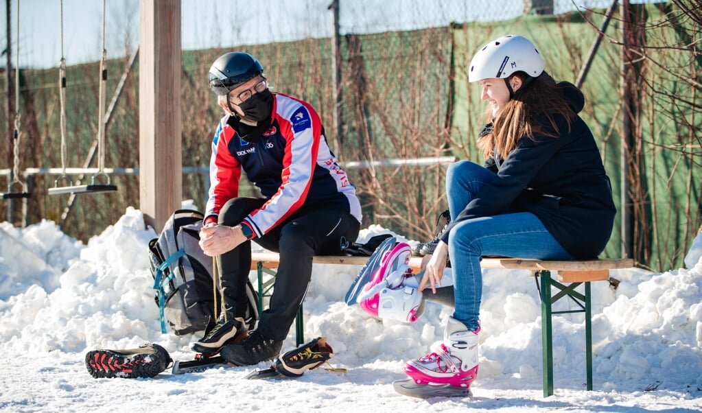 Schaatstrainer Hans Silvis met Aliene Boele op een bankje langs de ijsbaan in Ede. ‘Zet een hoofddeksel op voordat je je schaatsen aandoet.' (beeld Jorik Algra)