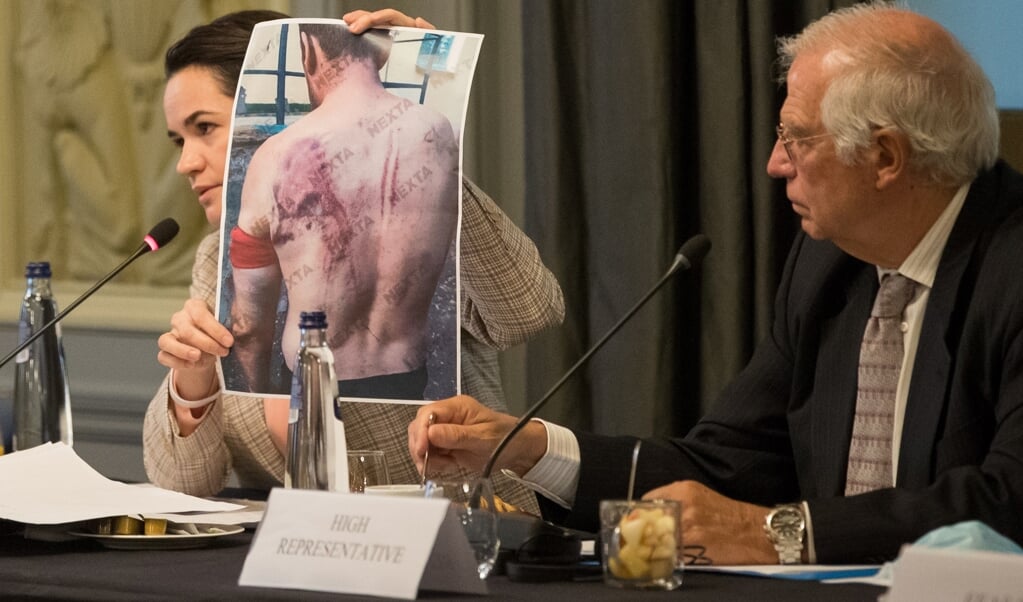 Oppositieleidster Svetlana Tichanovskaja laat een foto zien van een gemartelde man in Minsk; in Brussel kijkt Josep Borrell, Hoge vertegenwoordiger van de Europese Unie voor buitenlandse zaken en veiligheidsbeleid toe. (beeld epa / Stephanie Lecocq)