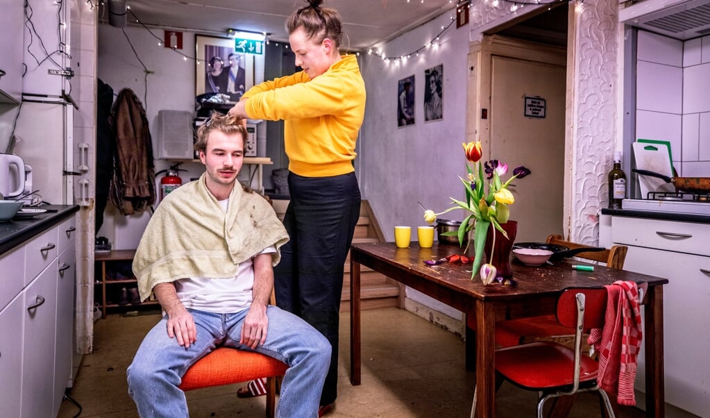 Gelegenheidskapper Yara Piekema voorziet Adriaan Walpot, een van haar dertien huisgenoten, van een nieuw kapsel. (beeld Raymond Rutting )