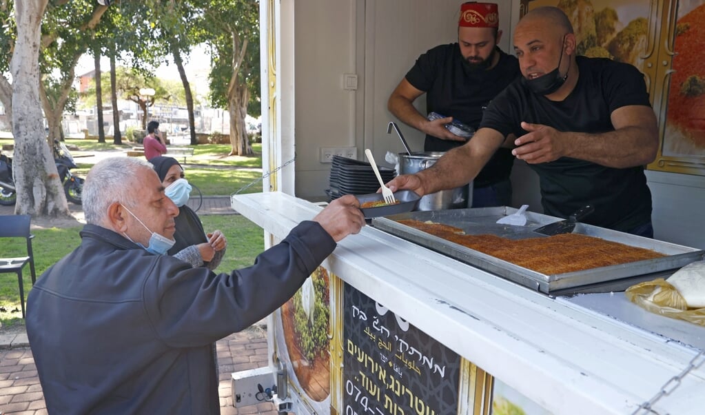 Een man in Tel Aviv krijgt een gratis stuk pizza nadat hij zich heeft laten vaccineren tegen corona. (beeld afp / Jack Guez)