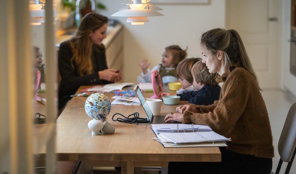 Een gezin met een oppas van een Amsterdamse oppasservice. Ouders die vanwege de lockdown thuiswerken en hun kinderen moeten helpen met thuisonderwijs schakelen steeds vaker een oppas in. (beeld anp / Jeroen Jumelet)