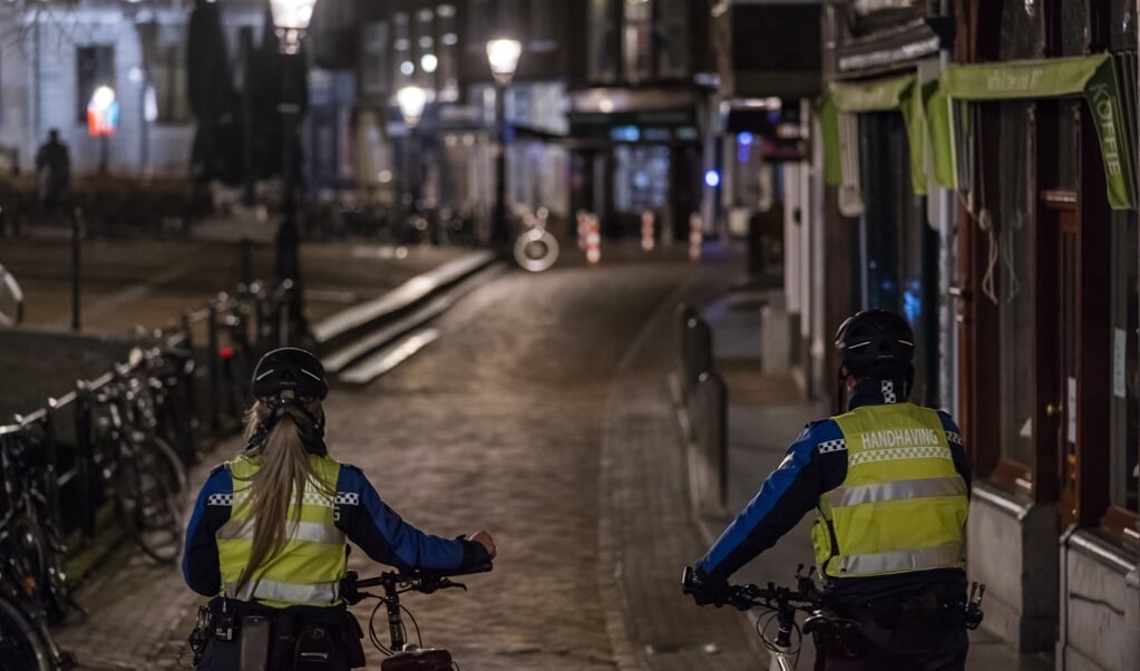 Handhavers lopen bij het ingaan van de avondklok door het centrum van Utrecht. (beeld anp / Jeroen Jumelet)