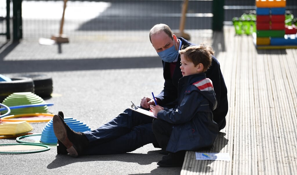 Prins William praat met een kind op het schoolplein in Londen. Hij bracht er samen met zijn vrouw Kate een werkbezoek in het kader van het project Mentally Healthy Schools. (beeld afp / Justin Tallis)
