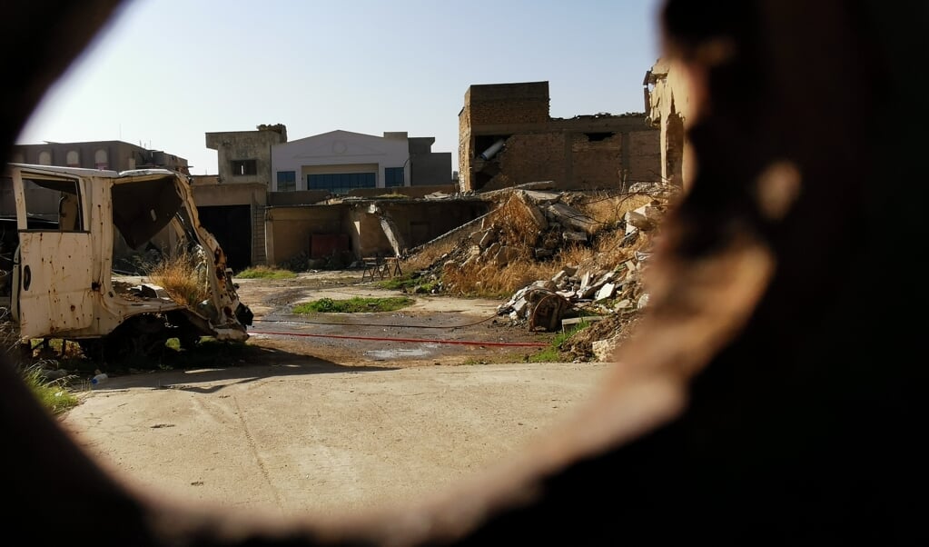 De binnenplaats van de Vrouwe van het Uur-kerk in Mosul, gezien door een kogelgat in de poort, ligt er troosteloos bij. (beeld Jacob Hoekman)