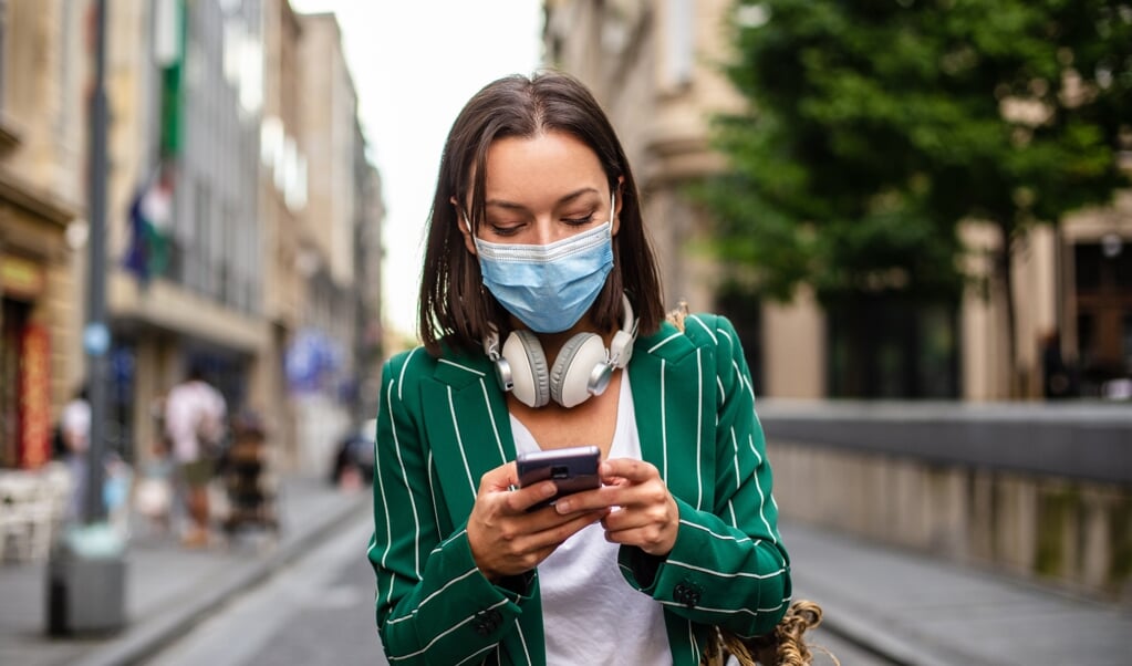 Mensen lopen tegenwoordig standaard met een telefoon in de hand, in connectie met iemand-op-afstand. (beeld istock / Smiljana Aleksic)