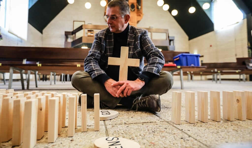 Dominee Ton van der Wekken legt aan de hand van vallende dominostenen de zondeval uit, en hoe Jezus de afstand heeft overbrugd. (beeld Maarten Boersema)