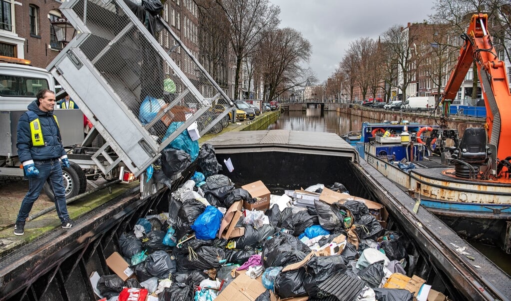 De Amsterdamse wethouder Laurens Ivens kijkt op de Kloveniersburgwal toe hoe de beunbak wordt gevuld. (beeld Guus Dubbelman)