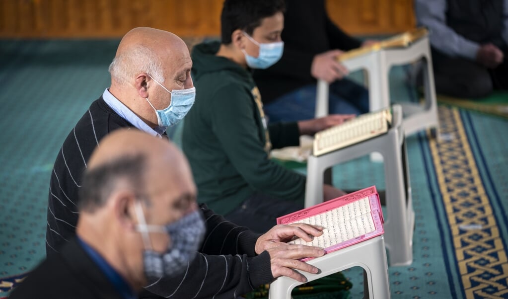 Enkele mannen reciteren de Koran in de Hilversumse Mevlana Moskee. Tijdens de Ramadan gebeurt dat grotendeels digitaal. (beeld anp / Jeroen Jumelet)