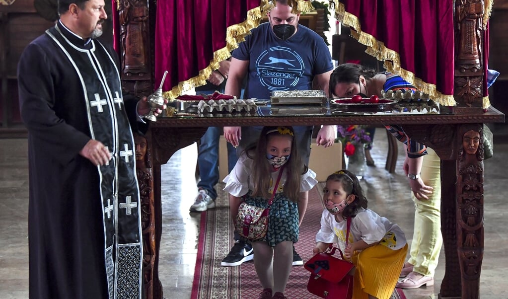 Noord-Macedonische kinderen kruipen tijdens de orthodoxe Goede Vrijdagviering onder een tafel door, die het graf van Jezus symboliseert. (beeld epa / Georgi Licovski)