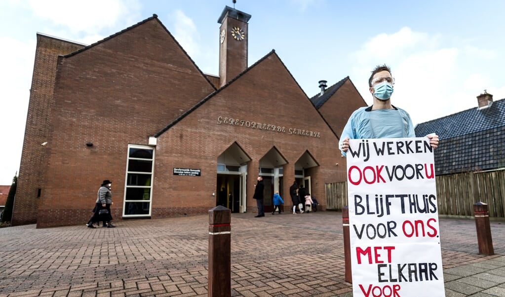 Bij een corona-uitbraak moet ook een kerk voor maximaal tien dagen gesloten kunnen worden, staat in een aangepast wetsvoorstel. Op de foto: zorgverlener Chris protesteerde in december 2020 tegen fysieke kerkdiensten bij de Rehobothkerk in Barneveld. (beeld anp / Remko de Waal)