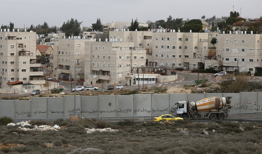 Een muur scheidt de Israëlische nederzetting Beit El van de Palestijnse hoofdstad Ramallah. (beeld afp Abbas Momani)