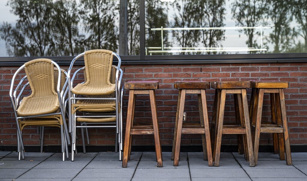 Barkrukken stoelen staan opgestapeld op het terras van voetbalvereniging Olympia in Gouda. (beeld anp / Tobias Kleuver)