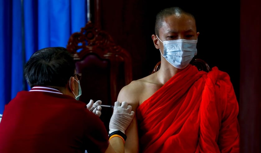 Een Boeddhistische monnik ontvangt het coronavaccin van AstraZeneca in Bangkok. (beeld epa / Diego Azubel)