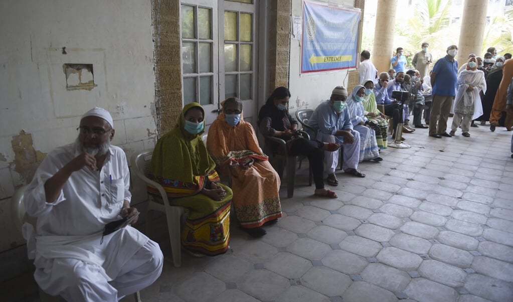Inwoners van Karachi (Pakistan) wachten om gevaccineerd te worden tegen het coronavirus. Het land ging vorige week in complete lockdown. Geld storten op Giro555 om sneller te vaccineren in deze landen is niet echt solidair. (beeld afp / Rizwan Tabassum)